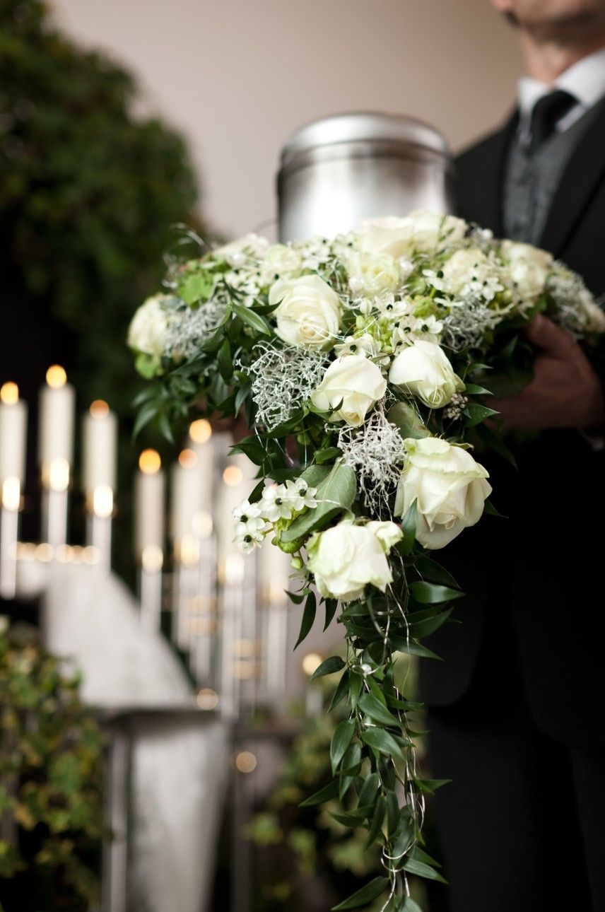 Eine Person trägt eine Urne dekoriert mit Rosen